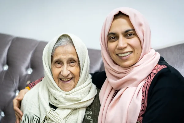 Portrait of very elder woman with daughter on sofa Portrait of woman hugging daughter with positive face. Third age, Home care concept. High quality photo
